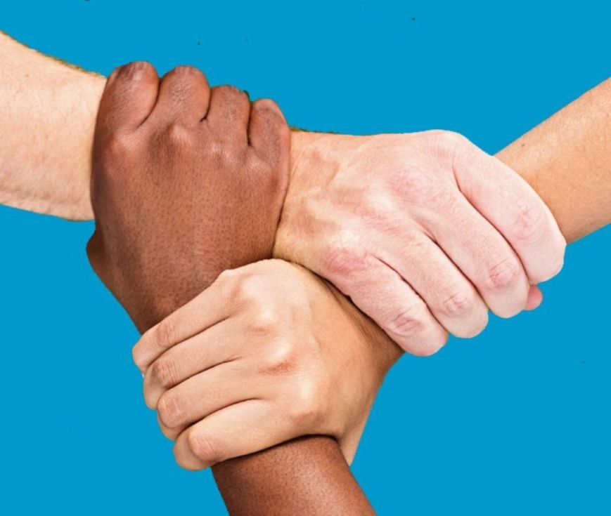 Three people with different skin colors holding each other’s wrists